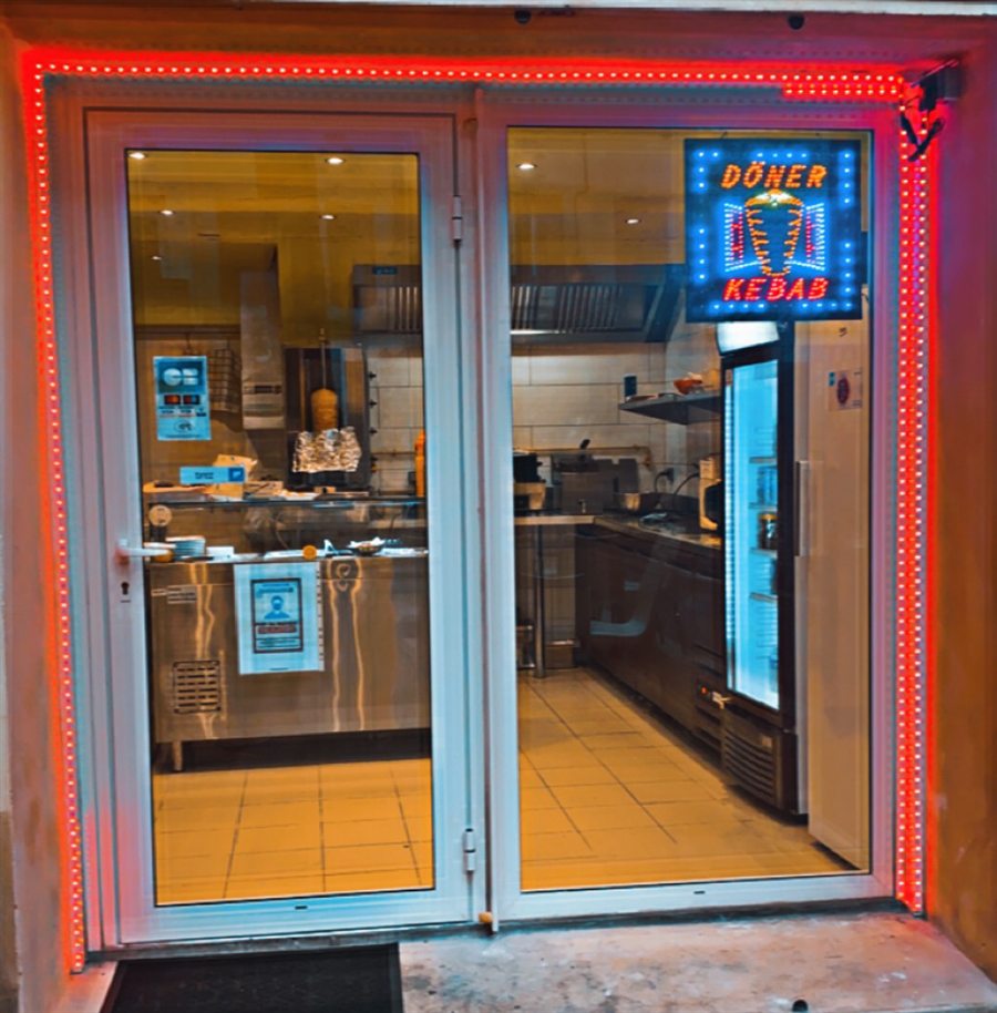 Devanture du restaurant éclairée par un néon rouge et l'enseigne Döner Kebab